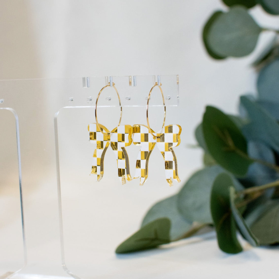 A pair of elegantGold and white checkered bow earrings, perfect for adding sophistication to any outfit.