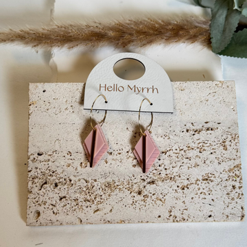 Dusty Rose layered Rhombus shaped earrings on a gold hoop hanging on  a Hello Myrrh branded card with a light background and greenery.