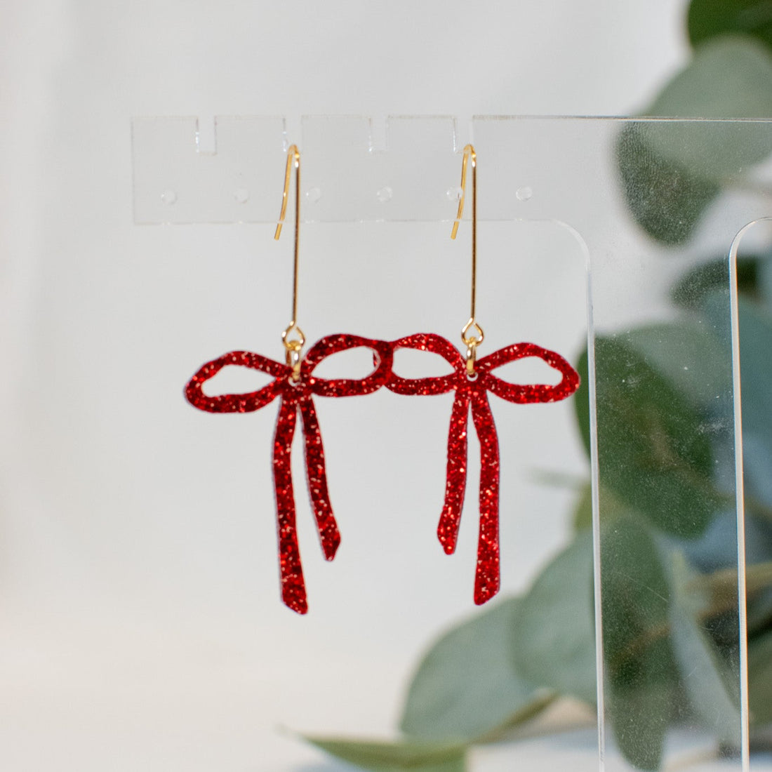 A pair of sparkling red glitter bow earrings, perfect for adding a playful and romantic touch to any outfit.