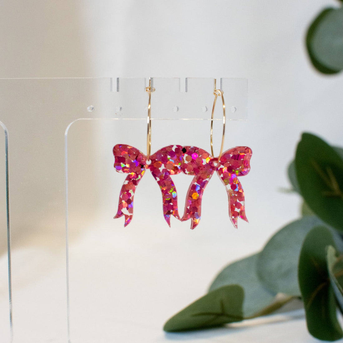 A pair of elegant pink glitter bow earrings, perfect for adding sophistication to any outfit.